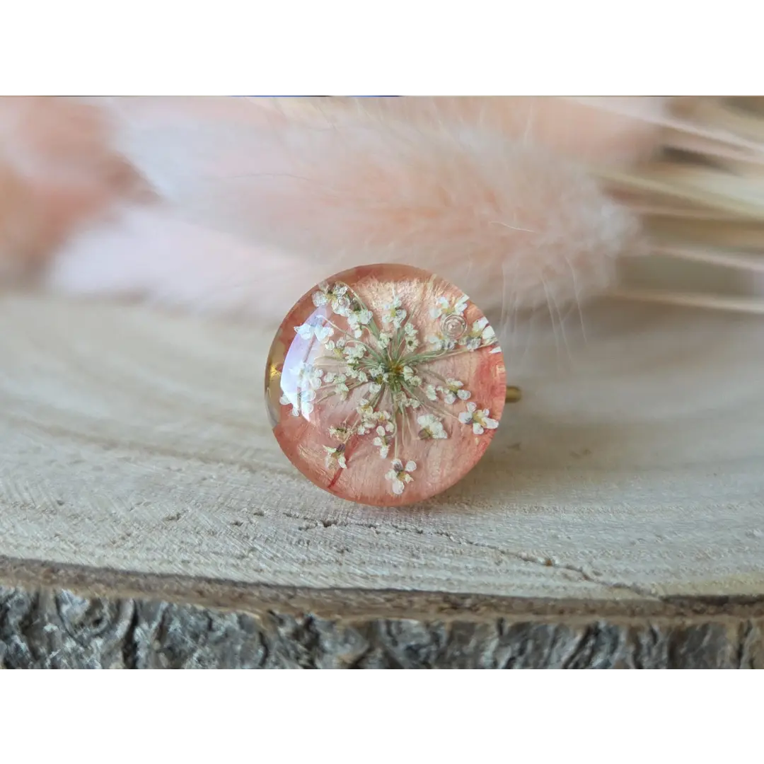 Anillo grande color coral pálido con clavel y flores de amimaju encapsuladas en resina transparente