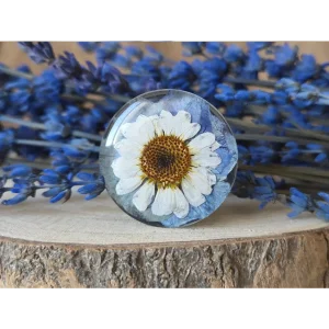 Broche redondo azul vintage con pensamiento y margarita preservadas en resina artesanal.