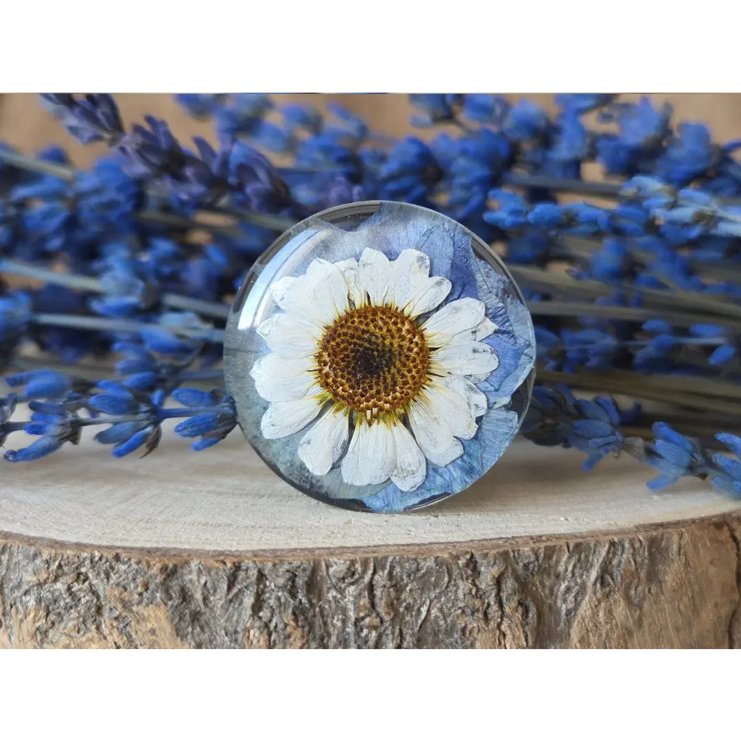 Broche redondo azul vintage con pensamiento y margarita preservadas en resina artesanal.