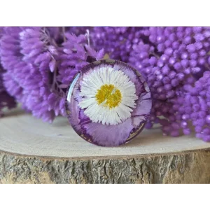 Broche redondo lila con clavel y margarita natural encapsulados en resina artesanal.