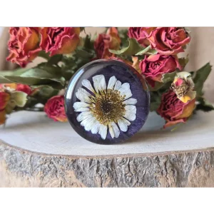 Broche morado oscuro hecho a mano con pensamiento y margarita natural encapsulados en resina.