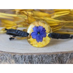 Pulsera amarilla con flor de verbena azul encapsulada en resina y detalle de banderita española