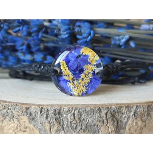 Pulsera azul océano con verbena y astilbe japónica en resina natural sobre fondo de madera
